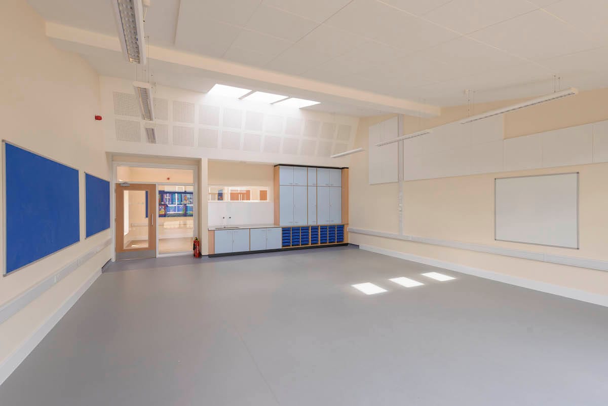 Empty classroom with blue bulletin boards and cabinets.