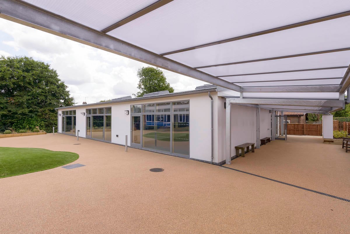 Modern school building with outdoor canopy and green space.