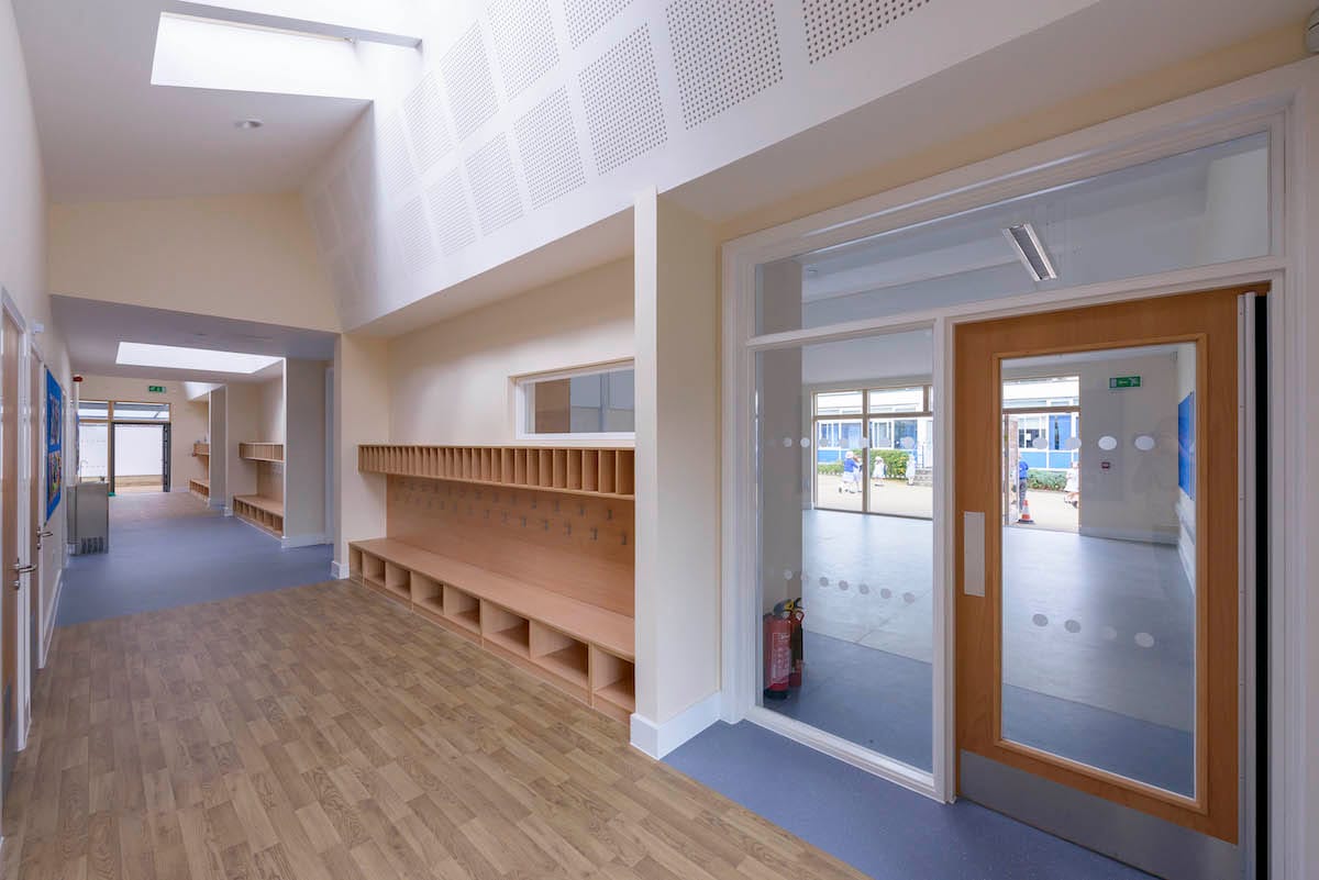 Bright school hallway with wooden cubbies and doors.