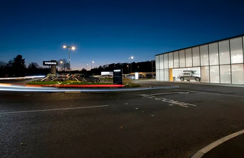 Car dealership at night with bright showroom display.