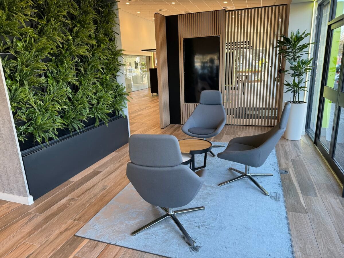 Modern lounge area with greenery and chairs.